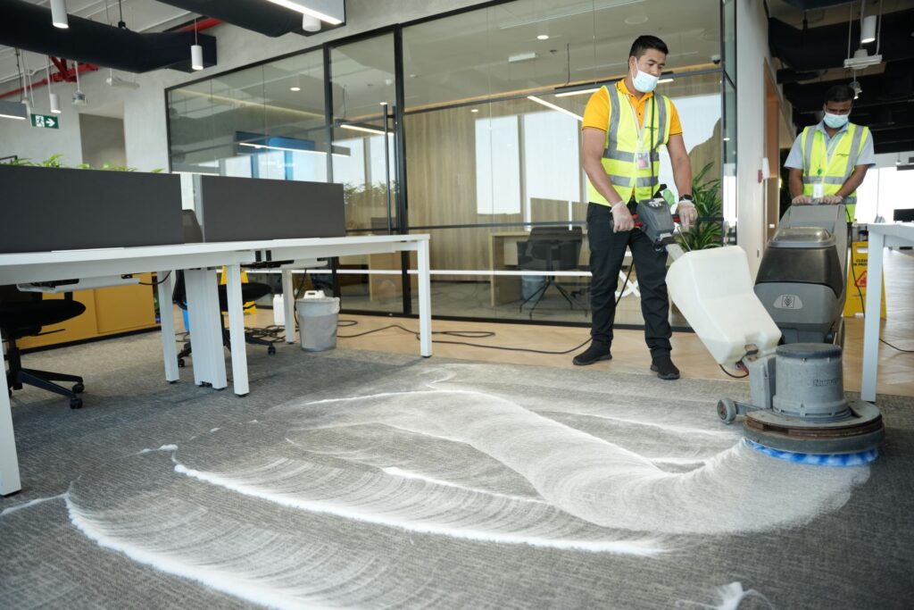 Cleaner scrubbing office carpet in Motor City, Dubai with rotary machine