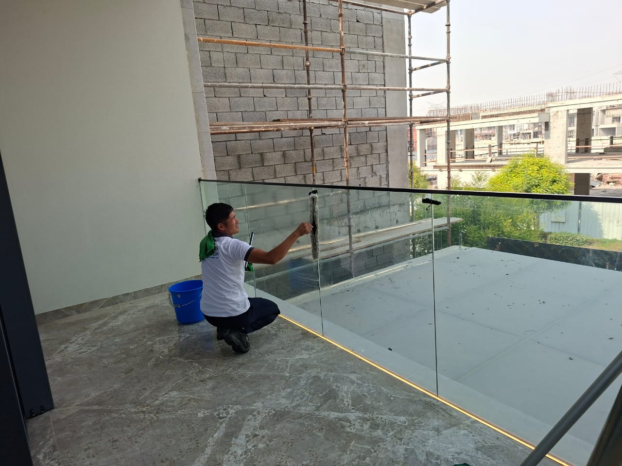 Technician cleaning balcony glass with professional tools in Dubai